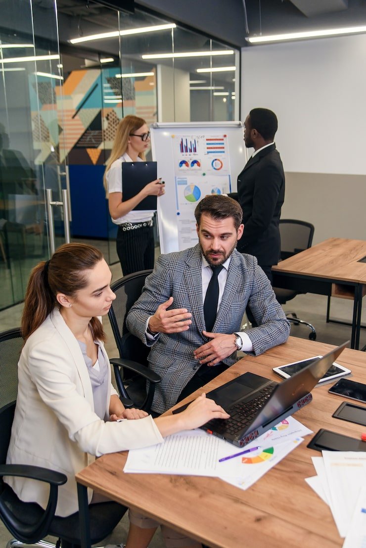 joined-work-two-confident-business-people-formal-suit-working-together-with-laptop_141188-5058